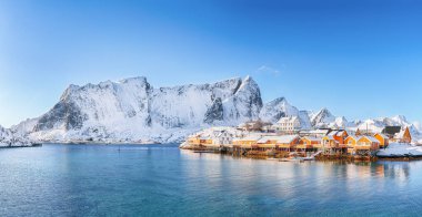 Arka planda Sakrisoy köyü ve karlı dağların kış manzarası. Lofotens 'ta popüler bir turizm merkezi. Konum: Sakrisoy, Moskenesoya, Lofoten; Norveç, Avrupa