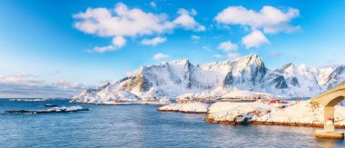 Arka plandaki Hamnoy ve karlı dağlardan Reine ve Sakrisoya köylerinin muhteşem kış manzarası. Konum: Olenilsoya Adası, Lofoten; Norveç, Avrupa