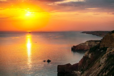 Cape Fiolent 'te gün batımında çimenler ve kayalar ön planda. Kırım