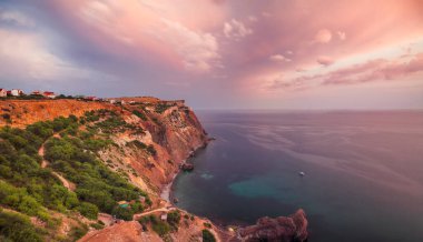 Cape Fiolent 'te gün batımında çimenler ve kayalar ön planda. Kırım