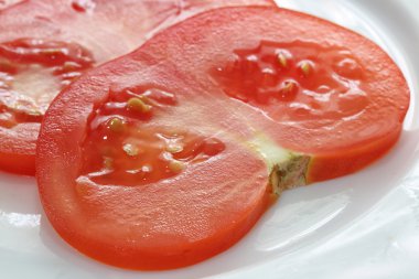 Beyaz tabakta dilimlenmiş domates.