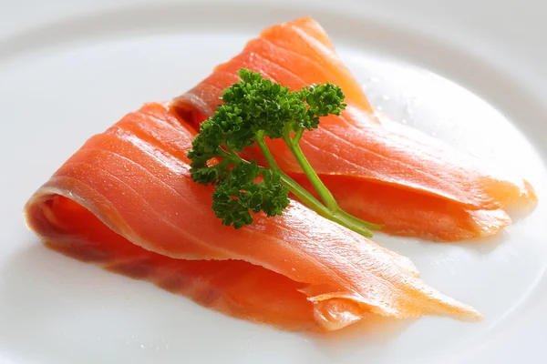 Fatias de salmão com salsa em uma chapa branca . — Fotografia de Stock