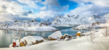 Küçük bir balıkçı köyünde çok kar ve Valberg yakınlarındaki karlı dağ zirveleriyle muhteşem bir kış manzarası. Konum: Valberg, Vestvagoy, Lofotens, Norveç