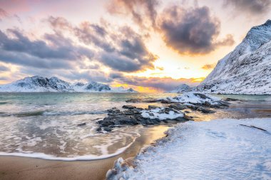Gün batımında Haukland plajı ve Leknes yakınlarında karlı dağ zirveleri ile inanılmaz bir kış manzarası. Konum: Leknes, Vestvagoy, Lofotens, Norveç