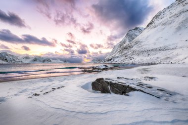 Günbatımında Haukland plajı ve Leknes yakınlarında karlı dağ zirveleri ile göz kamaştırıcı kış manzarası. Konum: Leknes, Vestvagoy, Lofotens, Norveç