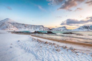 Gün batımında Haukland plajı ve Leknes yakınlarında karlı dağ zirveleri ile inanılmaz bir kış manzarası. Konum: Leknes, Vestvagoy, Lofotens, Norveç