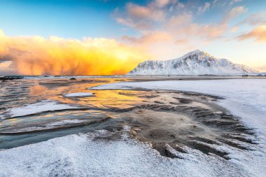 Skagsanden plajında güneş doğarken aydınlanan bulutlarla muhteşem bir kış manzarası. Popüler turizm merkezi. Konum: Flakstadoya Adası, Lofoten; Norveç, Avrupa