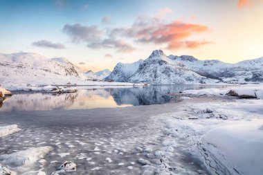 Flakstadpolen ve Boosen fiyortlarında güneş doğarken buzda çatlaklar ve Hustinden Dağı arka planda. Konum: Flakstadoya Adası, Lofoten; Norveç, Avrupa