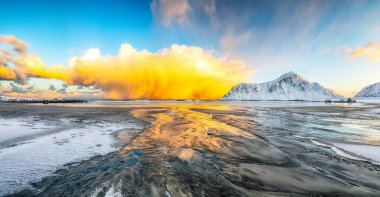 Skagsanden plajında güneş doğarken aydınlanan bulutlarla muhteşem bir kış manzarası. Popüler turizm merkezi. Konum: Flakstadoya Adası, Lofoten; Norveç, Avrupa