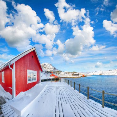 Sundstraumen Boğazı kıyısında geleneksel Norveç kırmızı ahşap evleri olan inanılmaz bir manzara. Konum: Flakstadoya Adası, Lofoten; Norveç, Avrupa
