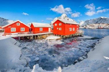 Reine Village ve Gravdalbukta Körfezi 'nde kışın güneşli manzarası var. Arka planda karlı dağ zirveleri. Konum: Reine, Lofoten; Norveç, Avrupa
