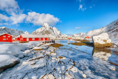 Reine Village ve Gravdalbukta Körfezi 'nde kışın güneşli manzarası var. Arka planda karlı dağ zirveleri. Konum: Reine, Lofoten; Norveç, Avrupa