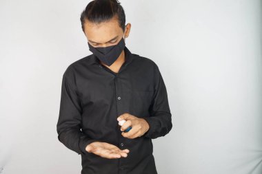 Maske takan genç bir adam, yüz maskesi, korona savaşçıları, dezenfektan görüntüsü kullanıyor. Vastav Kharat .