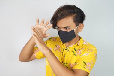 Maske takan genç bir adam, yüz maskesi, korona savaşçıları, dezenfektan görüntüsü kullanıyor. Vastav Kharat .