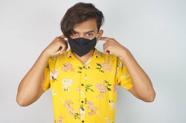 Maske takan genç bir adam, yüz maskesi, korona savaşçıları, dezenfektan görüntüsü kullanıyor. Vastav Kharat .