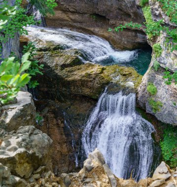 Ordesa Pirenesi 'ndeki güneşli bir arazide, kayanın yanında iki şelalede.