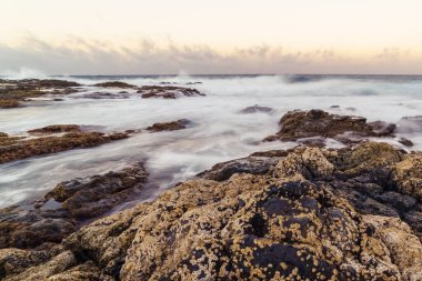 Kayaların arasında su bulunan deniz manzarası, kayalara çarpan dalgalar ve gökyüzünün yansımaları. Büyük Kanarya. İspanya
