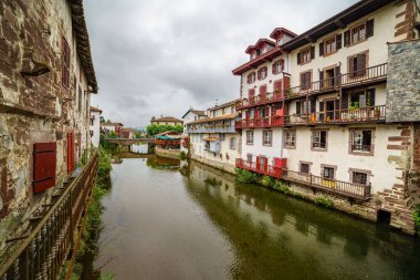 Su ve bulutlu gökyüzünde yansımaları olan nehir kanalı boyunca evler.