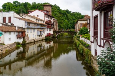 Su ve bulutlu gökyüzünde yansımaları olan nehir kanalı boyunca evler.