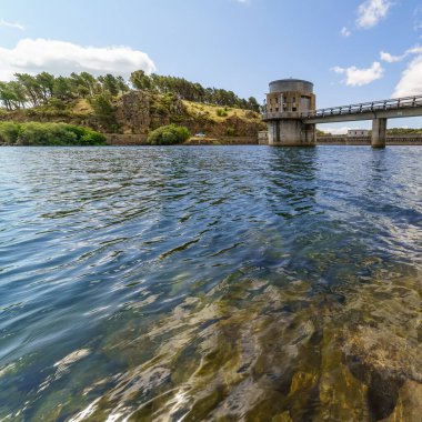 Bulutlu göl, mavi gökyüzü ve sudaki yansımalar. Atazar Barajı Madrid, İspanya