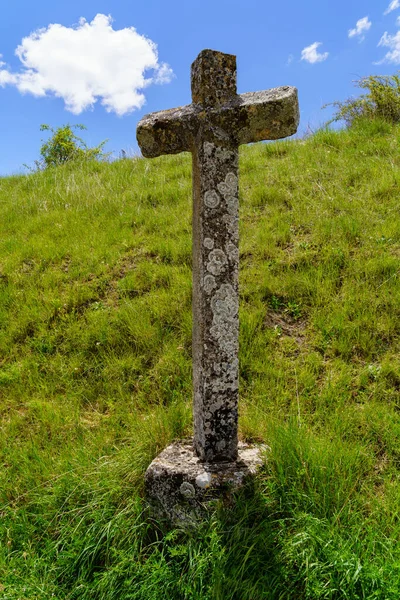 Stone cross on the green grass field