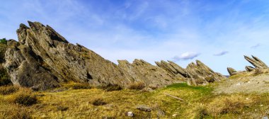 Yüksek kaya oluşumlarıyla dengelenmiş dağ manzarası, ağaçlar ve dağ yolu. Somosierra, İspanya
