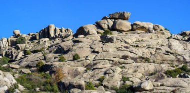 Büyük granit kayalardan oluşan dağ manzarası, çeşitli muhteşem şekillere sahip yüksek taş oluşumları. Şehir, Valdemanco, Madrid.