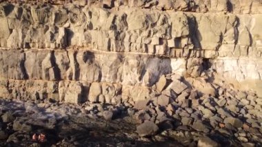 Büyük kayalar ve okyanus dalgalarıyla birlikte sakin bir günbatımında denizin kenarındaki uçurumun havadan görünüşü. Büyük Kanarya. Arginguin..