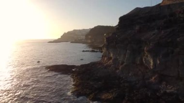 Büyük kayalar ve okyanus dalgalarıyla birlikte sakin bir günbatımında denizin kenarındaki uçurumun havadan görünüşü. Büyük Kanarya. İspanya.