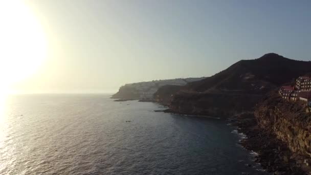 집들과 절벽을 공중에서 내려다볼 수있고 지평선에는 태양이 Gran Canaria Arguineguineguin — 비디오
