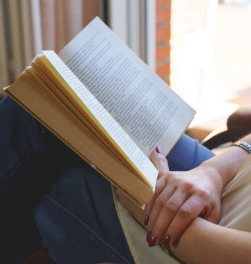 Beyaz kadın koltukta kitap okuyor dışarıda gün ışığında rahatlıyor. Uzayı kopyala Okuma, öğretme konsepti. Arkaplan.