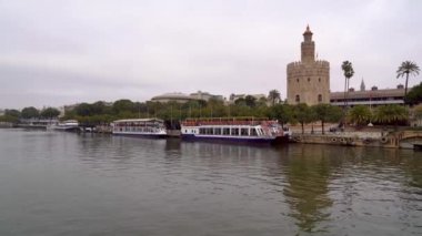 Torre del Oro ve sahildeki turist tekneleriyle Sevilla 'daki Guadalquivir nehri. Endülüs.
