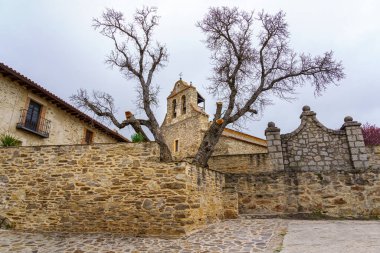 Ancient medieval church made of stone, seen among the trees with bare branches. Madrid.