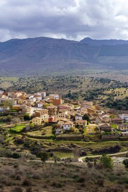 Dağlar ve yeşil bitkilerle çevrili vadideki eski kasabanın havadan görünüşü. Paredes Buitrago Madrid.