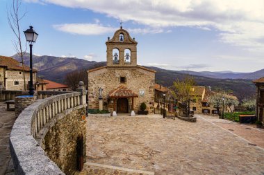 Eski evleri ve bulutlu mavi gökyüzü olan ortaçağ köyündeki antik taş kilise. La Hiruela Madrid 'de. Avrupa.