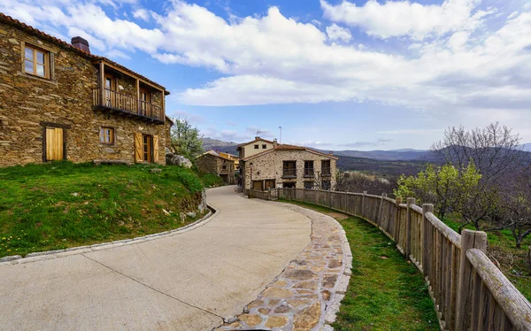 Kavisli caddesi ve bahçenin yanında ahşap çitleri olan eski bir kasaba caddesi. La Hiruela Madrid 'de. İspanya.