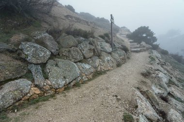 Çok soğuk bir günde yoğun sis varken dağ yürüyüşü için dağ yolu. Morcuera Madrid.
