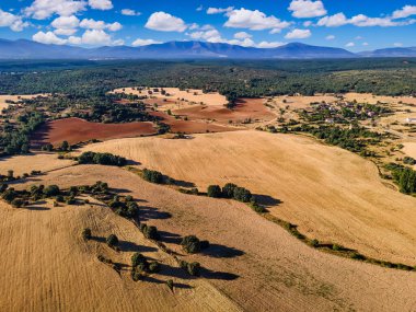 Mavi gökyüzü ve arka planda dağlar olan tarıma elverişli tarlaların havadan görüntüsü. Segovia.