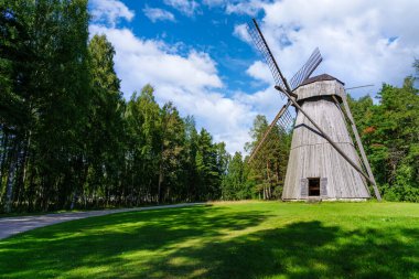 Çayırların ve bulutlu gökyüzünün üzerinde eski ahşap yel değirmeni.