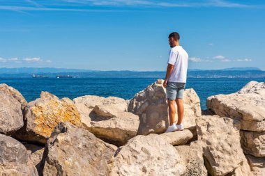 Turist, Slovenya 'nın Adriyatik Denizi' ndeki Piran kentini çevreleyen kayalara tırmanıyor