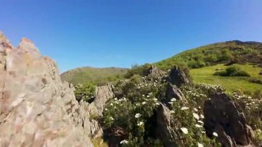 Madrid, Somosierra dağlarında ilkbaharda çiçek kaplı kaya oluşumları arasında uçan insansız hava aracı.