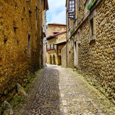 Eski binaların kaldırımlı zemini ve taş duvarları olan dar resimli cadde, Santillana del Mar, Cantabria.