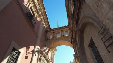 Güneşli bir günde İspanya 'da Valencia şehir merkezindeki tarihi binalar arasında bir kemer.