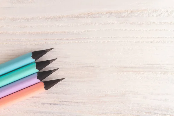 Pencils in delicate pastel colors, pink, mint, blue, lilac on a white wooden background. Copy space