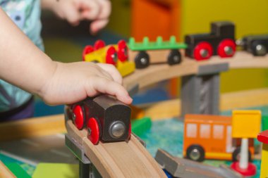 Bir çocuk ahşap bir demiryolu oyuncağıyla oynuyor.