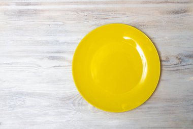 Beyaz ahşap bir masada sarı bir tabak. Boşluğu kopyala.