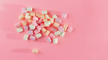 Pembe arka planda pastel tonlarda renkli marşmelovlar..