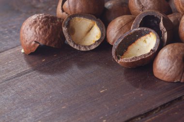 Kahverengi ahşap bir masaya Macadamia fındık kabukları yakın.