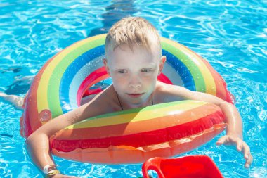 Beyaz çocuk yaz havuzunda şişirilebilir bir çemberde yüzüyor..