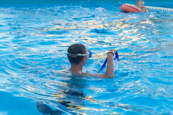 Boy swims in the pool in a mask and snorkel in the summer.